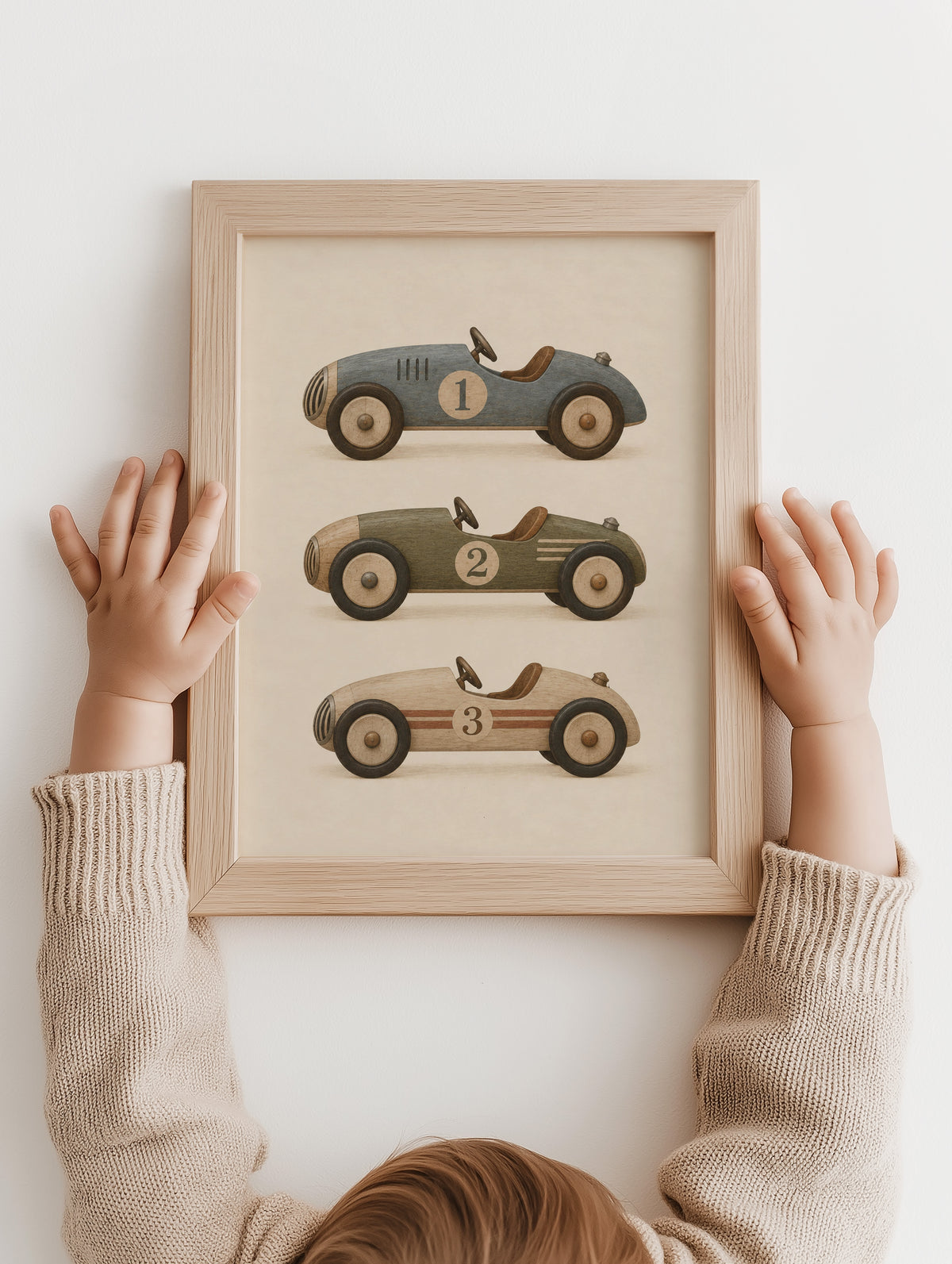 Kinderhanden bij een ingelijste poster met drie vintage raceauto's
