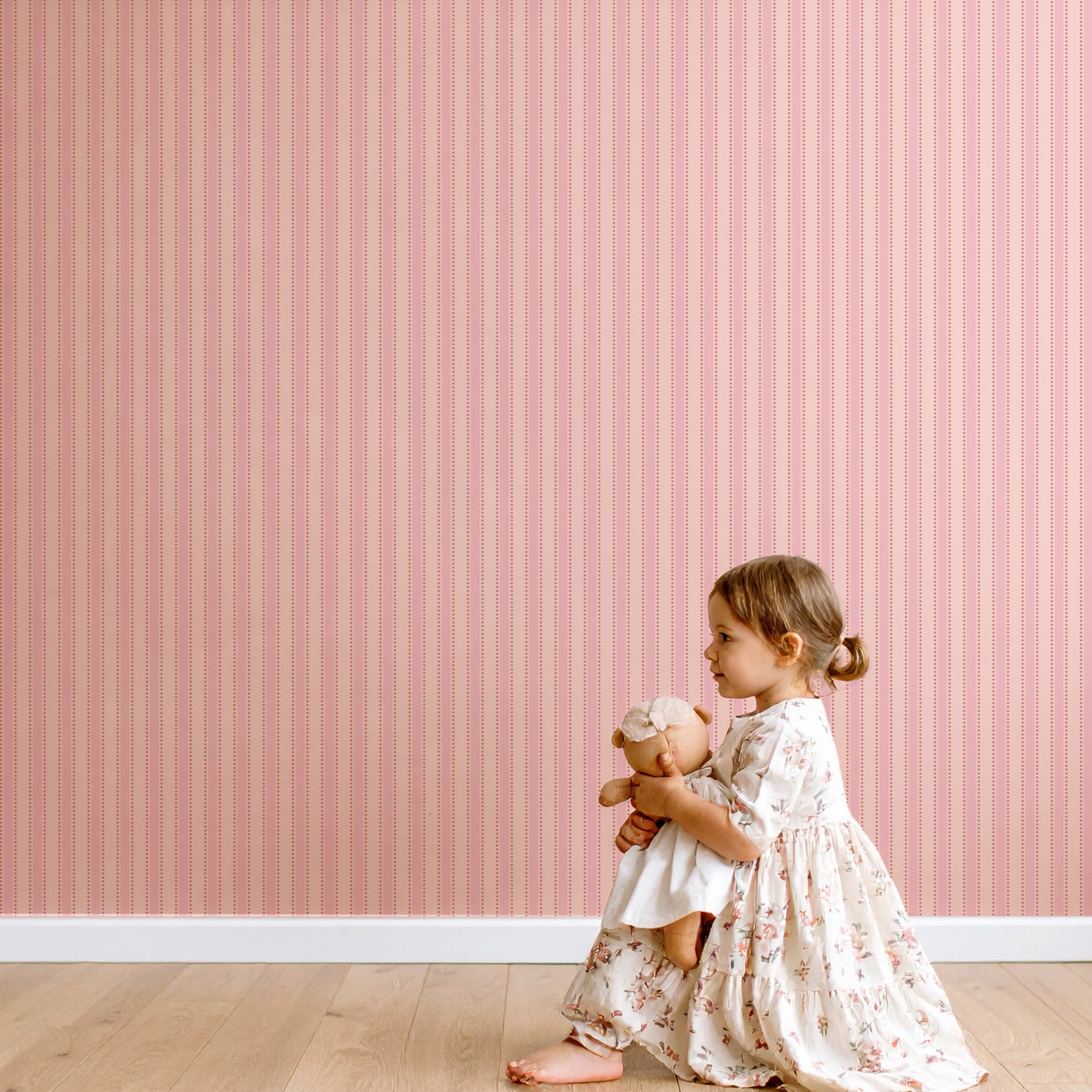 Poederroze gestreept behang in een kinderkamer met een spelend meisje